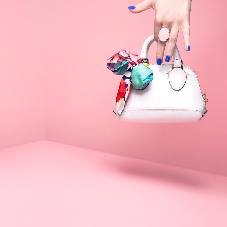 Someone holding a purse with a pink background